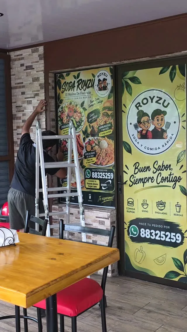 Ventanal de Soda Royzu con microperforado impreso: logo, platillos y el teléfono de pedidos