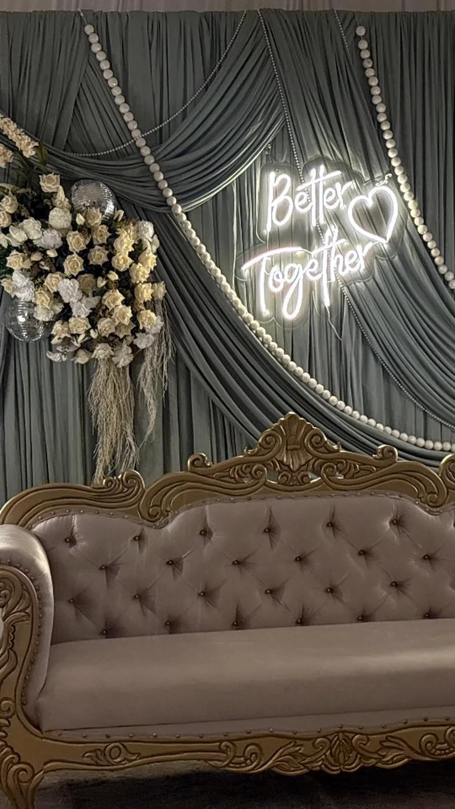 Neón blanco con la frase Better Together sobre cortinas grises en una decoración de boda